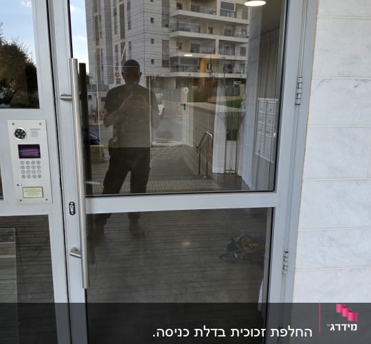 דלת זכוכית בכניסה לבניין עם מסגרת אלומיניום וידית נירוסטה